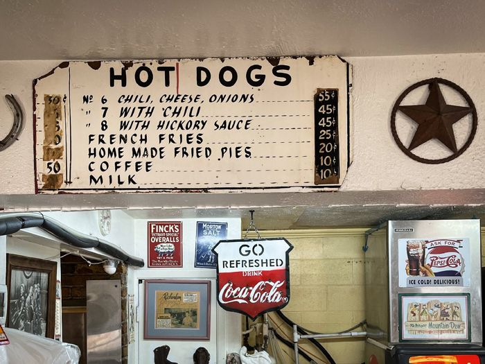 Vintage hand-painted hot dog menu sign above the counter at Del's Charcoal Burgers